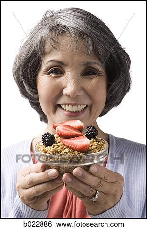 Stock Photograph - senior woman with a bowl of cereal and strawberries. Fotosearch