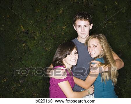 Stock Image - teenage boy and two teenage girls hugging. Fotosearch