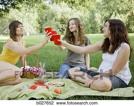 three young women having a picnic on the grass in a park View Large Photo Image Stock Image - three young women having a picnic on the grass in a park. Fotosearch