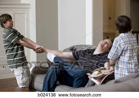 two sons pulling their father off the sofa View Large Photo Image Stock Photo - two sons pulling their father off the sofa. Fotosearch