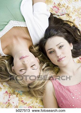 two women lying down on a floral print blanket outside View Large Photo Image Stock Image - two women lying down on a floral print blanket outside. Fotosearch