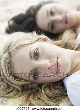 two women lying down on a floral print blanket outside View Large Photo Image Stock Photo - two women lying down on a floral print blanket outside. Fotosearch