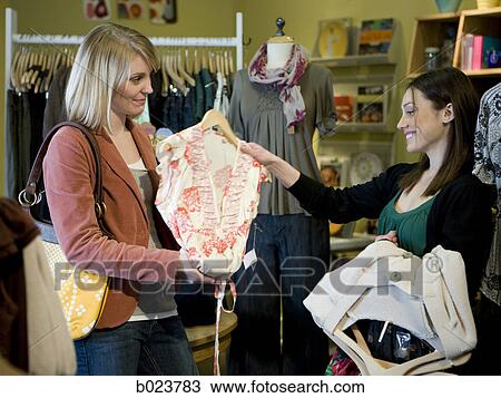 Stock Image - two women shopping for clothes. Fotosearch