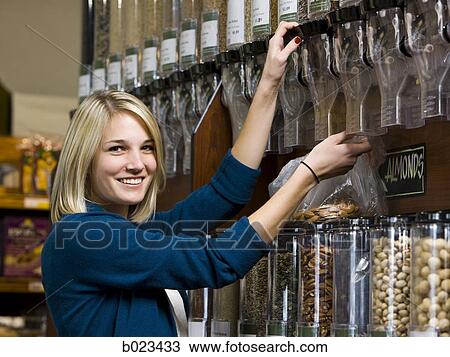 Stock Image - woman buying nuts at the supermarket. Fotosearch