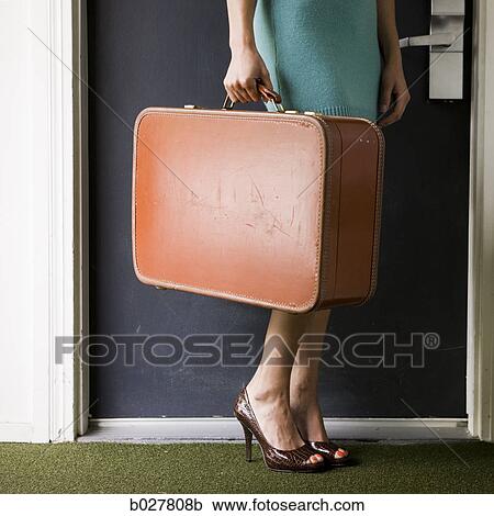 woman carrying a suitcase outside a door View Large Photo Image Stock Image - woman carrying a suitcase outside a door. Fotosearch