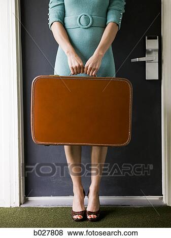 woman carrying a suitcase outside a door View Large Photo Image Stock Photo - woman carrying a suitcase outside a door. Fotosearch