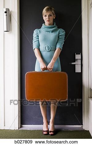 woman carrying a suitcase outside a door View Large Photo Image Stock Photo - woman carrying a suitcase outside a door. Fotosearch