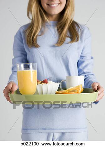 Stock Image - woman carrying breakfast on a tray. Fotosearch