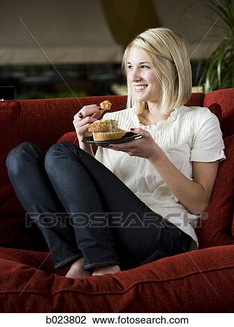 woman eating a muffin on a red sofa View Large Photo Image Stock Image - woman eating a muffin on a red sofa. Fotosearch