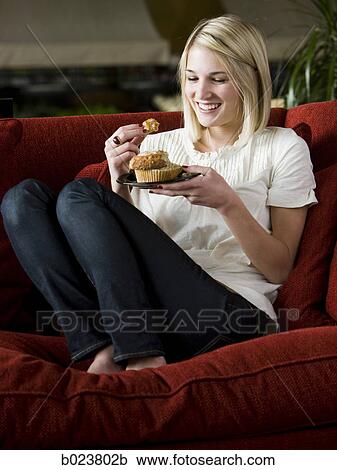 woman eating a muffin on a red sofa View Large Photo Image Stock Image - woman eating a muffin on a red sofa. Fotosearch