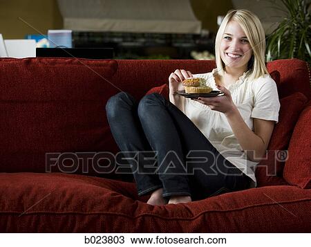 woman eating a muffin on a red sofa View Large Photo Image Stock Image - woman eating a muffin on a red sofa. Fotosearch