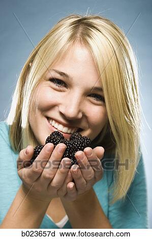 Stock Image - woman eating blackberries. Fotosearch