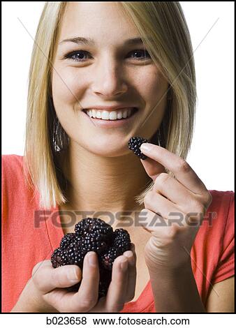 Stock Photo - woman eating blackberries. Fotosearch