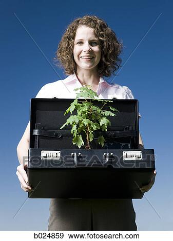 Stock Photo - woman holding a briefcase with a tree in it. Fotosearch