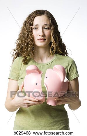 Stock Photo - woman holding a broken piggy bank. Fotosearch