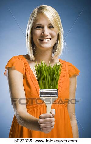 Stock Photography - woman holding a grass paintbrush. Fotosearch