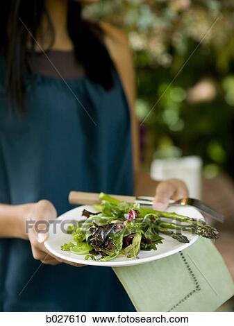 Stock Image - woman holding a plate of vegetables. Fotosearch