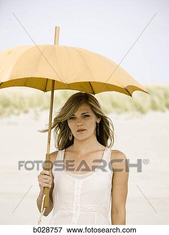 Stock Photo - woman holding an umbrella at the beach. Fotosearch