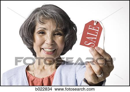 Picture - woman holding "sale" tag. Fotosearch