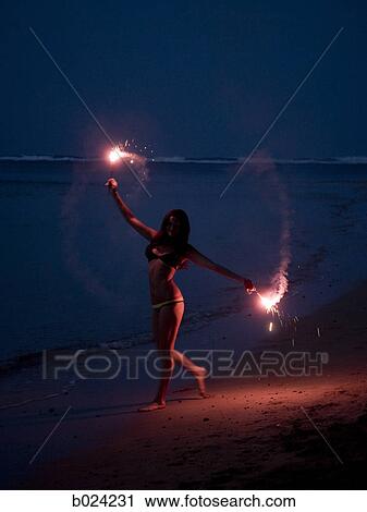 woman holding sparklers on the beach at night View Large Photo Image Stock Image - woman holding sparklers on the beach at night. Fotosearch
