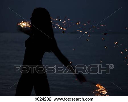 woman holding sparklers on the beach at night View Large Photo Image Stock Image - woman holding sparklers on the beach at night. Fotosearch