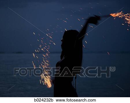 woman holding sparklers on the beach at night View Large Photo Image Stock Image - woman holding sparklers on the beach at night. Fotosearch