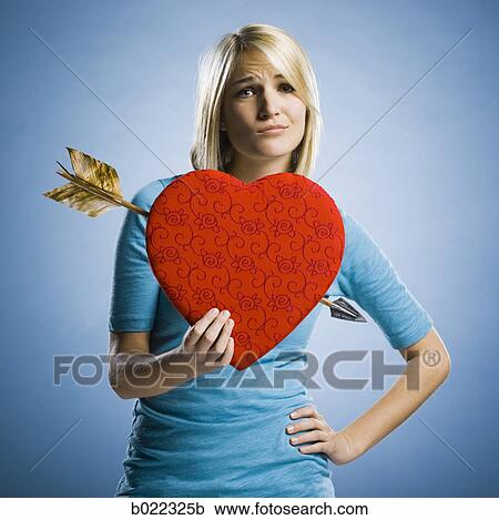 woman holding up a heart with an arrow through it View Large Photo Image Stock Image - woman holding up a heart with an arrow through it. Fotosearch
