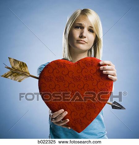 woman holding up a heart with an arrow through it View Large Photo Image Stock Photography - woman holding up a heart with an arrow through it. Fotosearch