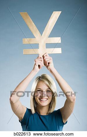 Stock Image - woman holding up a yen symbol. Fotosearch