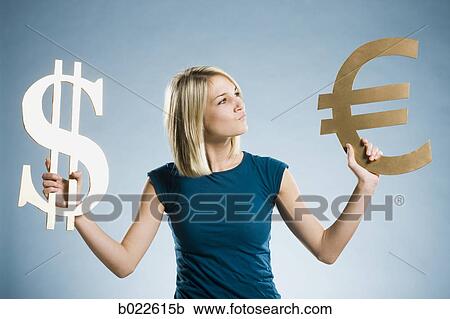 Stock Image - woman holding up currency symbols. Fotosearch