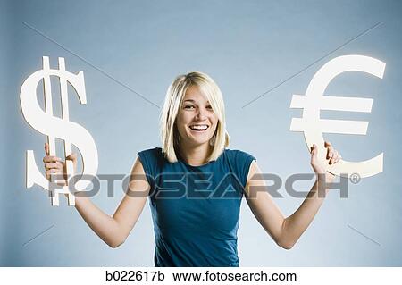 Stock Image - woman holding up currency symbols. Fotosearch