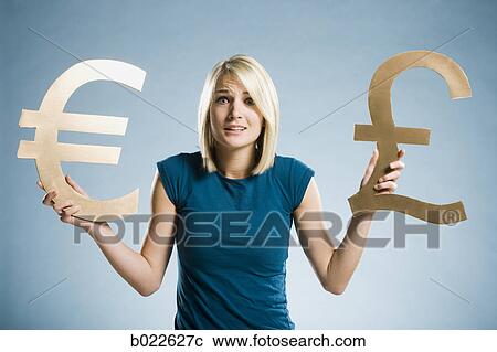 Stock Image - woman holding up currency symbols. Fotosearch