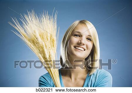 Stock Image - woman holding up wheat. Fotosearch