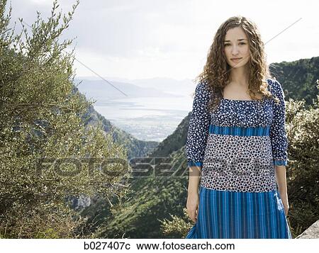 Stock Image - woman in a floral print dress on a mountain top. Fotosearch