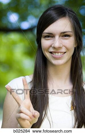 woman in a white shirt making the peace sign View Large Photo Image Picture - woman in a white shirt making the peace sign. Fotosearch