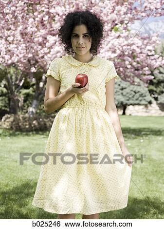 Stock Photograph - woman in a yellow dress with a red apple. Fotosearch