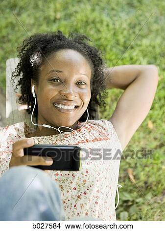 woman in the backyard listening to a digital music player View Large Photo Image Picture - woman in the backyard listening to a digital music player. Fotosearch