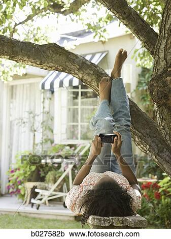 Stock Image - woman in the backyard listening to a digital music player. Fotosearch
