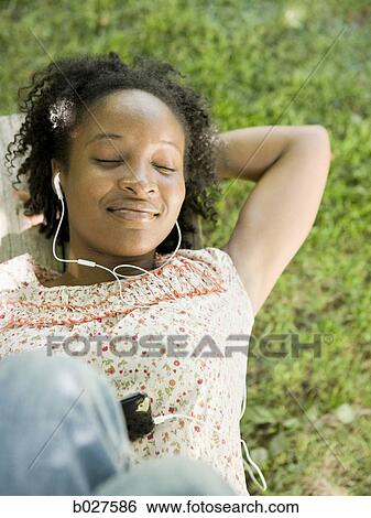 woman in the backyard listening to a digital music player View Large Photo Image Stock Photograph - woman in the backyard listening to a digital music player. Fotosearch