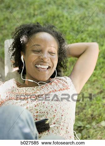 woman in the backyard listening to a digital music player View Large Photo Image Stock Photography - woman in the backyard listening to a digital music player. Fotosearch