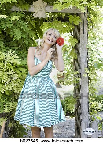 Stock Photography - woman in the garden in a summer dress. Fotosearch