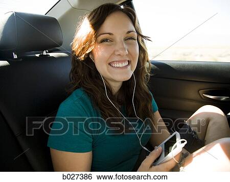 woman listening to digital music on her ipod while riding in the car View Large Photo Image Stock Photograph - woman listening to digital music on her ipod while riding in the car. Fotosearch