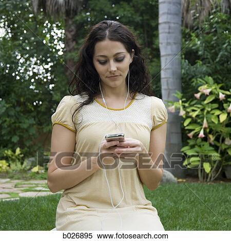 Stock Photography - woman listening to ipod outdoors. Fotosearch