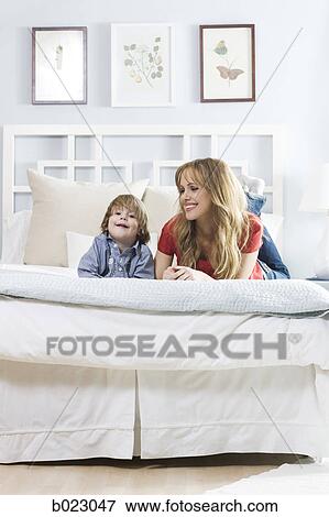 woman lying on a bed with her son View Large Photo Image Stock Photo - woman lying on a bed with her son. Fotosearch