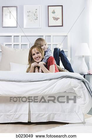 Stock Photo - woman lying on a bed with her son. Fotosearch