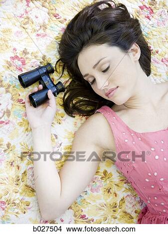 Picture - woman lying on a floral print blanket. Fotosearch