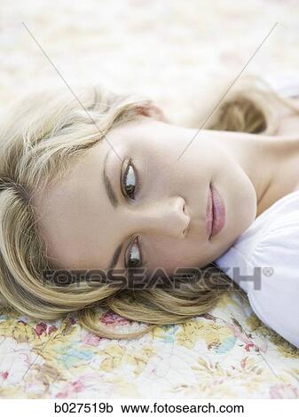 Stock Image - woman lying on a floral print blanket. Fotosearch