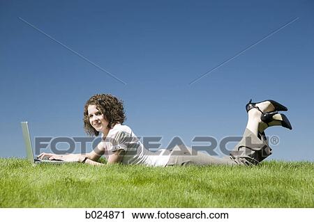 woman lying on the grass using a laptop View Large Photo Image Stock Image - woman lying on the grass using a laptop. Fotosearch