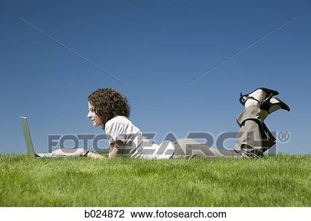 woman lying on the grass using a laptop View Large Photo Image Stock Image - woman lying on the grass using a laptop. Fotosearch