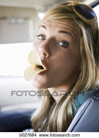 woman making duck lips with potato chips in her mouth View Large Photo Image Picture - woman making duck lips with potato chips in her mouth. Fotosearch